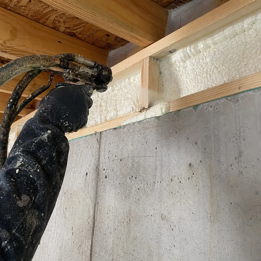 Professional contractor applying spray foam insulation to a residential rim joist
